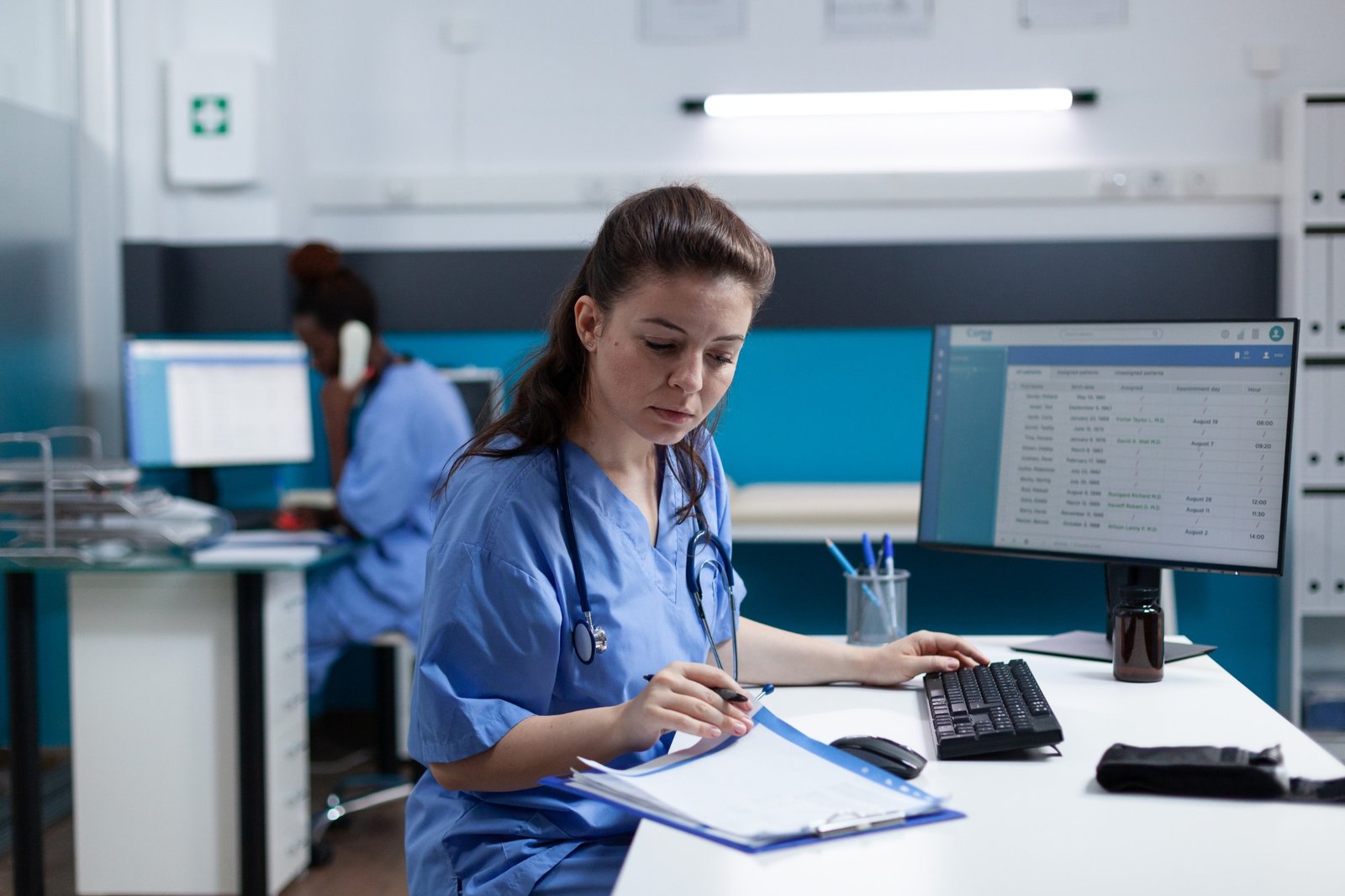 Nurse managing patient records at a computer in a medical practice