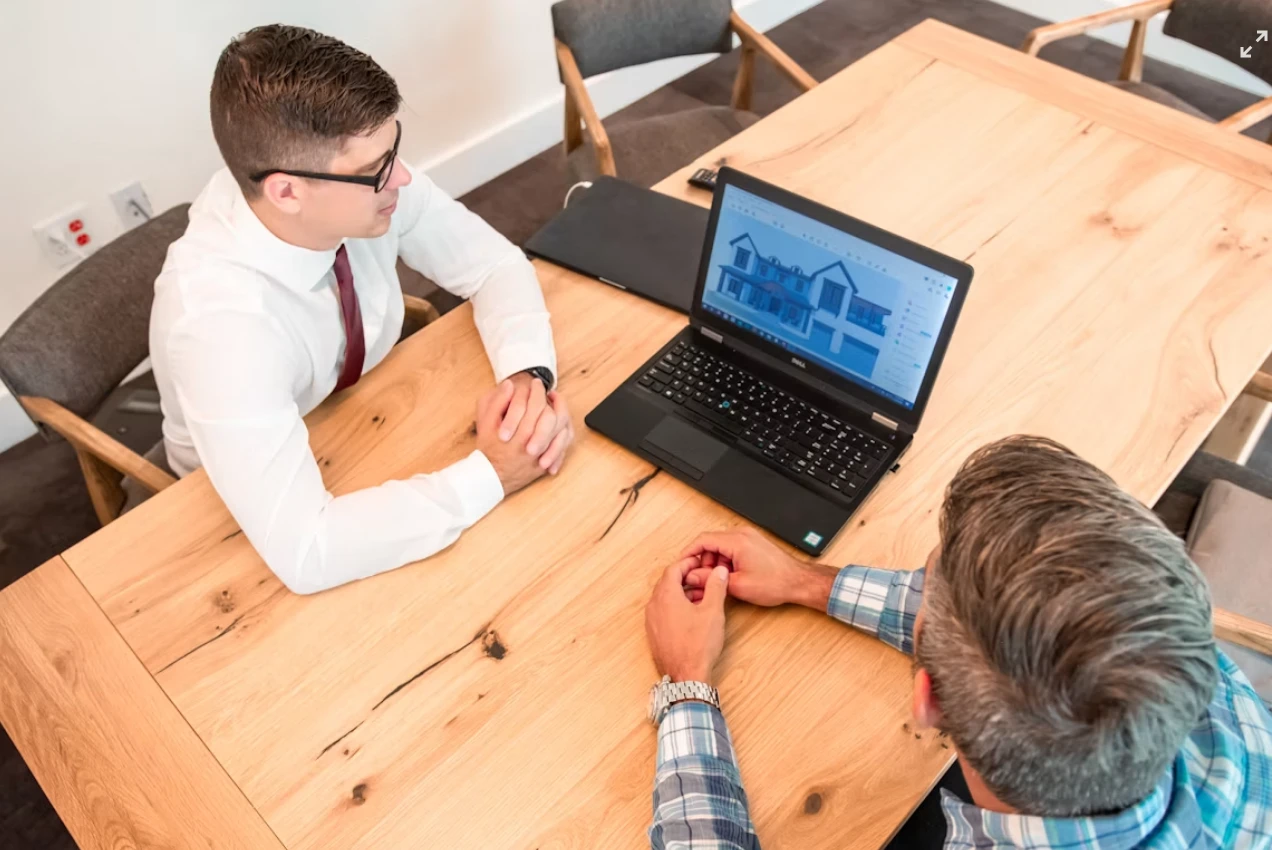 Consultant in a one-to-one meeting with a client at a laptop